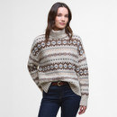 Woman wearing a patterned turtleneck sweater with jeans. The sweater features earthy tones and geometric designs, creating a cosy and relaxed look.