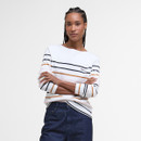 Young woman with braided hair wearing a striped sweater and dark jeans, arms crossed. The expression is confident and poised, against a white background.