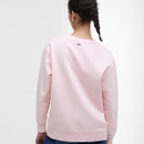 Rear view of a person with braided hair wearing a pastel pink sweatshirt, showcasing the garment's back and tiny logo detail, creating a casual tone.