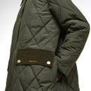 Close-up of a quilted olive-green jacket with a corduroy patch and button details. The brand name is embroidered in yellow on the patch, conveying a classic style.