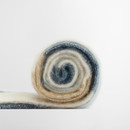 A multicoloured, fluffy knit blanket is tightly rolled in a spiral. The blanket features soft blue, cream, and beige hues, creating a cosy feel against a light gray background.