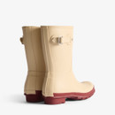 The back of a pair of short Hunter wellingtons with a natural coloured upper and a contrasting red sole.