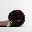 A rolled-up multicoloured wool blanket against a plain white background, featuring warm hues of black, red, brown, and yellow, evoking cosiness.