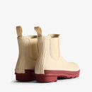 The back of a pair of Chelsea boot Hunter wellingtons with a natural coloured upper and a deep red sole.