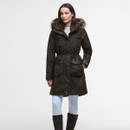 Woman in a dark brown parka with fur-lined hood and large pockets, wearing white pants and brown boots, posing against a neutral background.