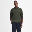 Man wearing a dark green sweater and navy pants stands confidently against a white background. His expression is calm and relaxed.