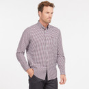 Man wearing a red and white checkered button-up shirt and black pants stands with a relaxed pose, one hand in pocket, against a plain background.