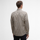 A man is seen from behind wearing a yellow and blue checkered shirt paired with dark jeans, set against a plain white background.