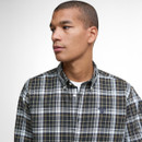 Young man gazes to his left, wearing a plaid button-up shirt. The tone is calm and contemplative, with a clean, neutral background.