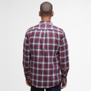 A person with a shaved head stands facing away, wearing a red, white, and blue plaid shirt. The background is plain white, emphasizing the shirt's pattern.