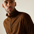 A man gazes off-camera, wearing a brown zip-neck jumper. The image conveys a calm, contemplative mood with a neutral background.