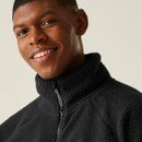 Zoomed-in portrait of a smiling man wearing the black fleece jacket zipped up, showcasing the high collar and front zip detail.