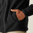 Close-up of the fleece's side pocket, with a hand inserted partway and the zip partially open, highlighting the texture and functional design.