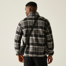 Rear view of a man wearing a black and grey checkered borg fleece jacket with a black crossbody bag, showcasing the relaxed fit and dropped shoulder seams.