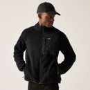 Mid-body shot of model wearing black Frankie fleece with hands in pockets, styled with tonal baseball cap.