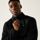 Close-up of a male model zipping up the funnel neck of the FRANKIE black borg half-zip fleece, highlighting the soft fleece texture and branded chest pocket.