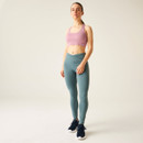 Model in Dare 2b lilas sports bra and teal leggings standing in a relaxed, full-body pose with navy trainers.