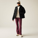 A full length view of a woman wearing a short black padded jacket with red trousers and trainers.