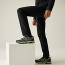 Close-up side view of Regatta Highton waterproof black trousers, worn by a male model with one leg raised on a white plinth, showcasing the flexible fit and articulated knees for enhanced movement.