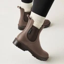 Brown ankle wellington boots with dark elastic side panels, rear pull tabs and rugged black tread soles, worn with cream socks.