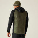 Man in olive puffer jacket and green beanie, facing away. The jacket's quilted texture and his relaxed posture denote a casual, outdoor vibe.