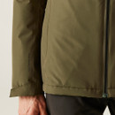 Close-up of a person's lower torso and hand, wearing an olive-green jacket with a vertical zip. The jacket sleeve reads "Isotex 15000." Minimalist and functional design.