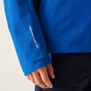 Close-up of a person's hand touching the Velcro fastening on a blue jacket sleeve with "Isotex Stretch 10000" text, conveying outdoor functionality.