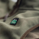Detail shot of the Ridgeline Monarch gilet in deep forest green, focusing on the Ridgeline logo patch and smooth fleece texture.