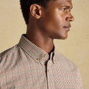Profile close-up of a man wearing a classic checked shirt in beige, burgundy, and navy, featuring a button-down collar and top-stitch detailing.