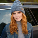 Front-facing portrait of model in slate blue bobble beanie – Handcrafted cable knit design with thick ribbed brim, worn with casual winter layering for comfort and warmth.