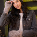 Model in thoughtful pose, wearing mushroom-coloured chunky cable-knit handwarmers and a matching headband, lifting one hand to her forehead, dressed in a black denim jacket and cream jumper.
