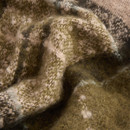 Close-up of a textured, fluffy fabric with a mix of olive green and beige tones. The material appears soft, with delicate patterns and a cosy feel.