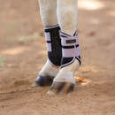 Close-up of a horse’s lower legs wearing LeMieux protective brushing boots in black with lavender straps, standing on sandy ground.