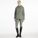 Woman wearing a sage green hooded pullover jacket with a half-zip front and large front pocket, paired with matching sage green riding leggings and black tall riding boots, standing against a plain white background.