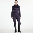A full-body studio shot of the woman in the deep purple quilted-front jacket and matching leggings, paired with tall black riding boots, standing with her hands relaxed at her sides. A full-body studio shot of the woman in the deep purple quilted-front jacket and matching leggings, paired with tall black riding boots, standing with her hands relaxed at her sides.