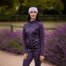 A woman standing in front of purple flowering bushes, wearing a purple quilted-front jacket, matching leggings, and a light purple knitted headband, with a blurred wooden fence in the background. A woman standing in front of purple flowering bushes, wearing a purple quilted-front jacket, matching leggings, and a light purple knitted headband, with a blurred wooden fence in the background.