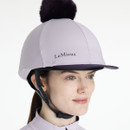 Lilac riding helmet silk with dark faux fur pom-pom and contrast navy peak trim, styled with a matching quarter-zip base layer.