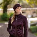 Woman outdoors wearing a LeMieux sparkle headband in damson, paired with a matching quilted jacket, standing in soft natural light.