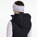 Rear view of a woman in a light purple “LeMieux” script headband and black padded gilet with hood, hair tied back in a low ponytail.