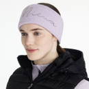 Side view of a woman wearing a light purple knitted “LeMieux” script headband, lilac base layer, and black padded gilet.