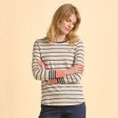 A person stands against a beige background, wearing a striped long-sleeve top with navy and orange stripes. Their arms are crossed, with a calm expression.