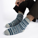 Man wearing Totes Toasties blue Fair Isle Sherpa slipper socks with slip-resistant tread