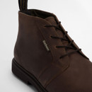 Close-up of dark brown leather chukka boot showing lace-up front, smooth leather finish and subtle branding.