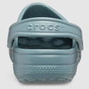 Close-up of a light blue Crocs shoe viewed from the back. The shoe features a textured footbed and heel strap with the logo embossed. Simple and casual.