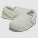 Soft, fluffy white slippers with a cosy texture and buttoned strap, set against a plain background. The slippers evoke warmth and comfort.