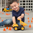 Smiling boy lifting the dumper bed of a JCB toy dump truck surrounded by play cones.