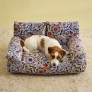 Wire Fox Terrier curled up on Joules floral sofa-style dog bed with cushioned back.