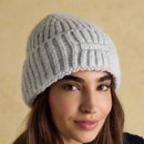 Woman wearing a grey knitted beanie hat with ribbed design, styled casually with a winter jacket.