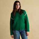 Woman wearing the Alexandra green jumper with relaxed fit and white stitching across the arms.