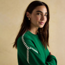 Close-up of the sleeve detail on the Alexandra jumper in green with decorative white stitching.